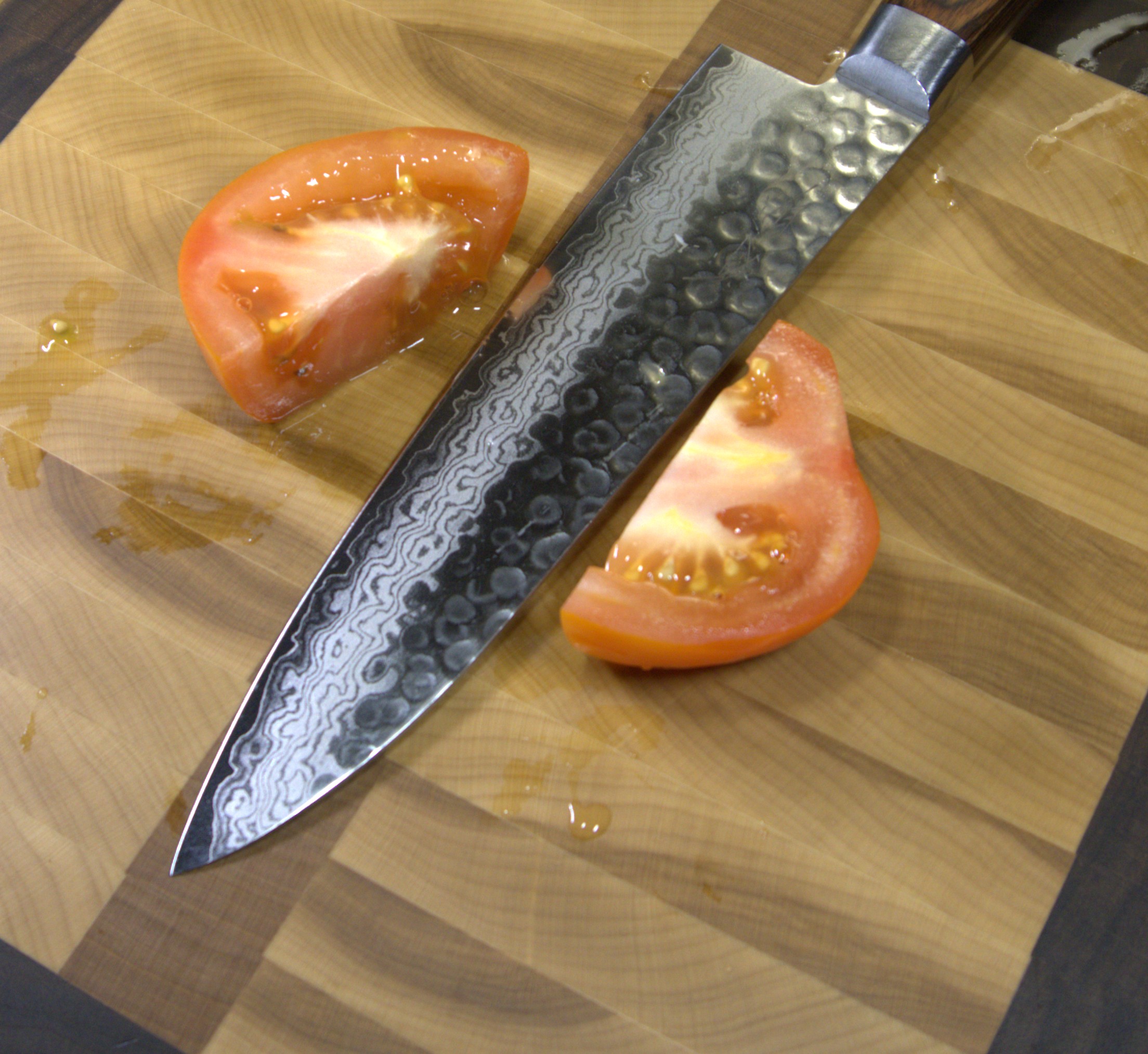 Damascus knife slicing tomato